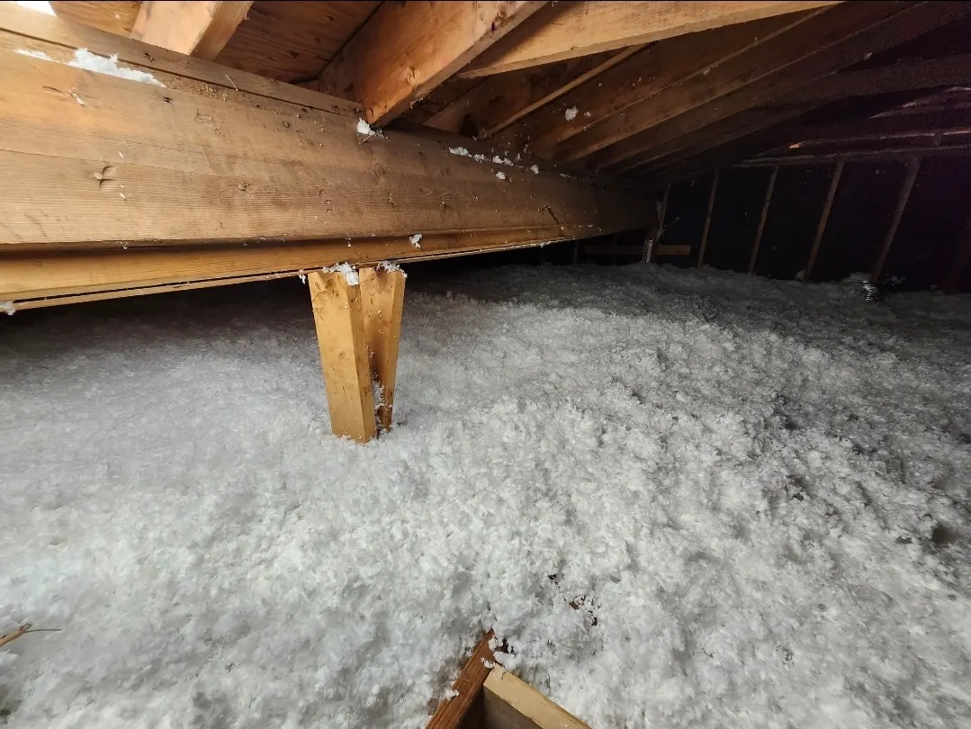 Thick layer of white blown-in insulation covering an attic floor