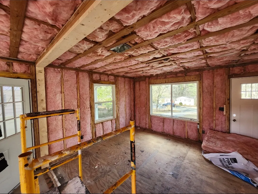 Pink fiberglass batts installed in the walls and ceiling of a room under renovation