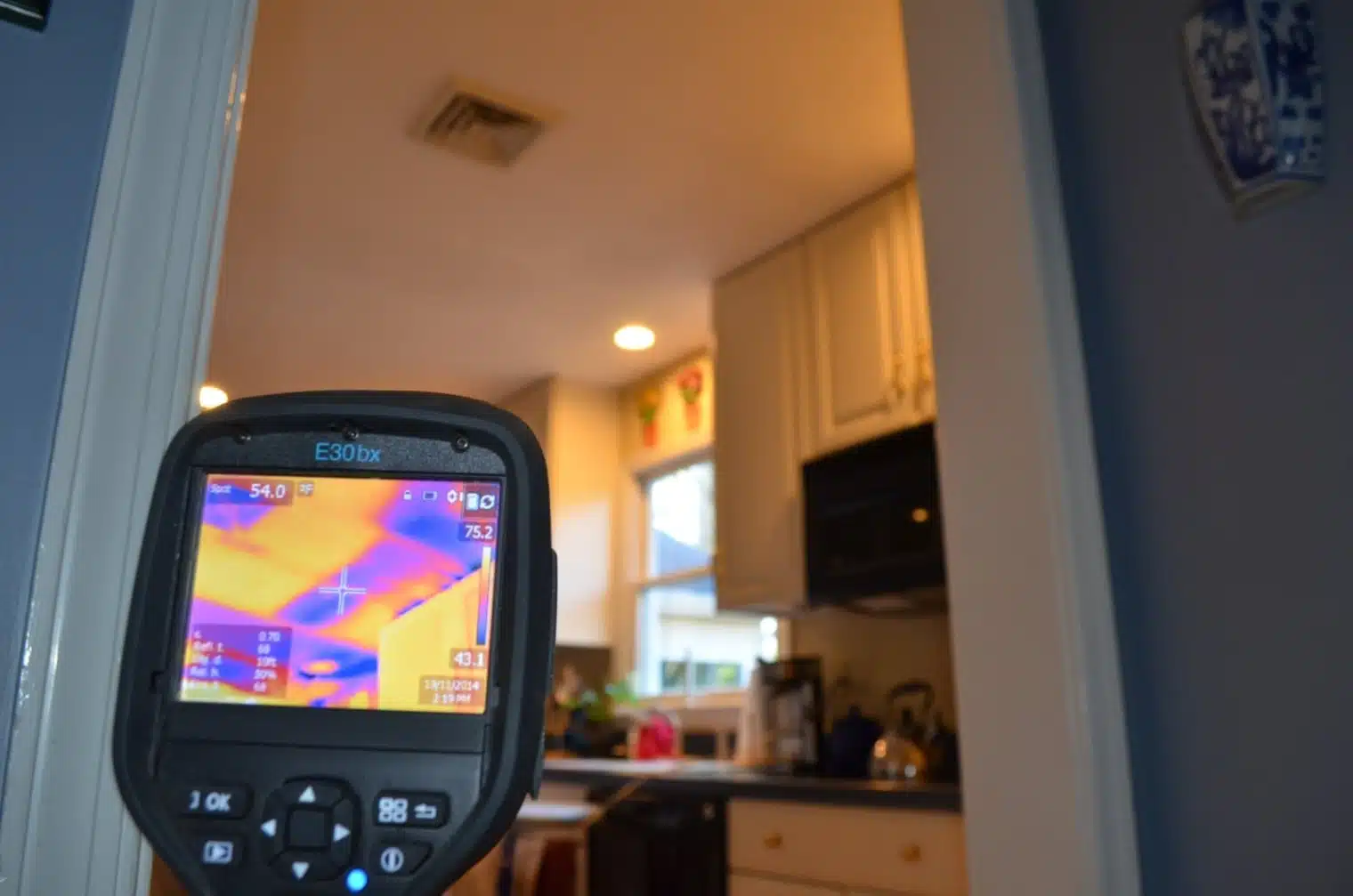Professional energy auditor using thermal camera to inspect an Alpharetta home's attic for hidden leaks and insulation needs before Makeover Insulation installs spray foam.